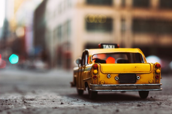 Yellow toy taxi from behind on a city street