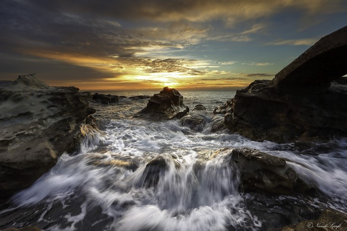 Waves crashing on rocks at sunset