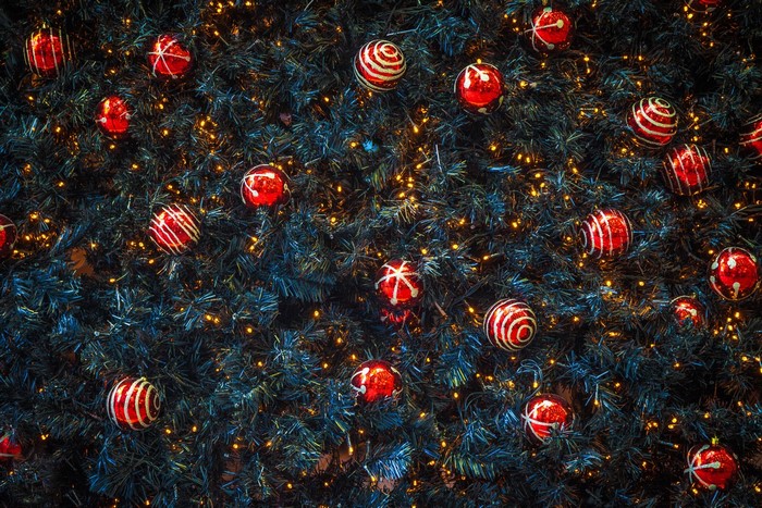 Red Christmas ornaments on a decorated Christmas tree with fairy lights