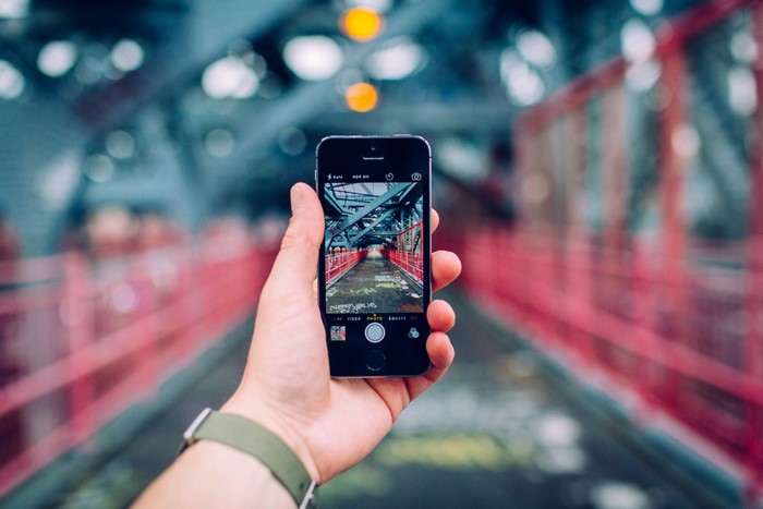 iPhone held up to photograph a bridge