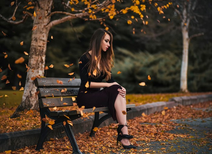Woman sitting on a park bench in autumn