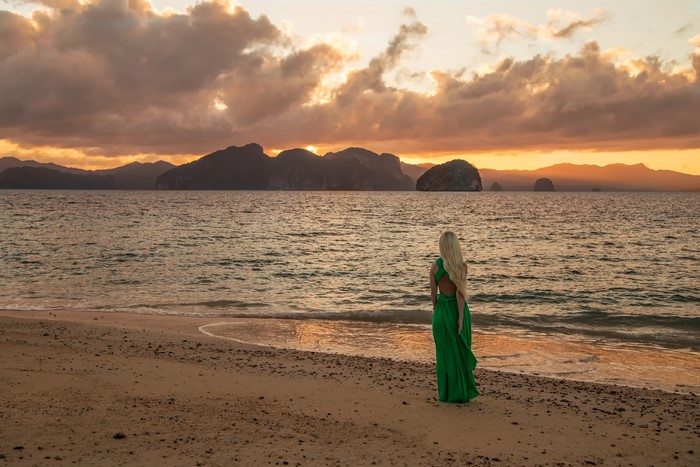 Woman in green dress on beach at sunset