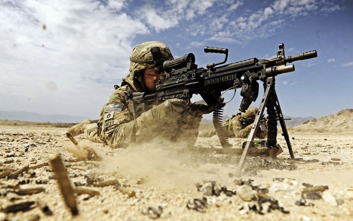 US Soldier firing a machine gun in a desert