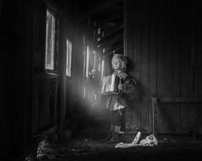 Boy playing accordion in abandoned building