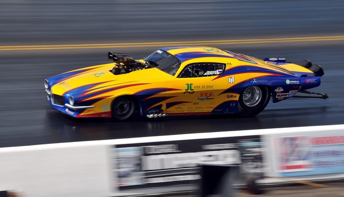 Drag racing car with yellow and blue livery on track