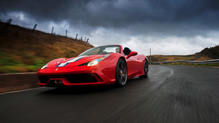 Red Ferrari 458 Speciale A driving on a wet road