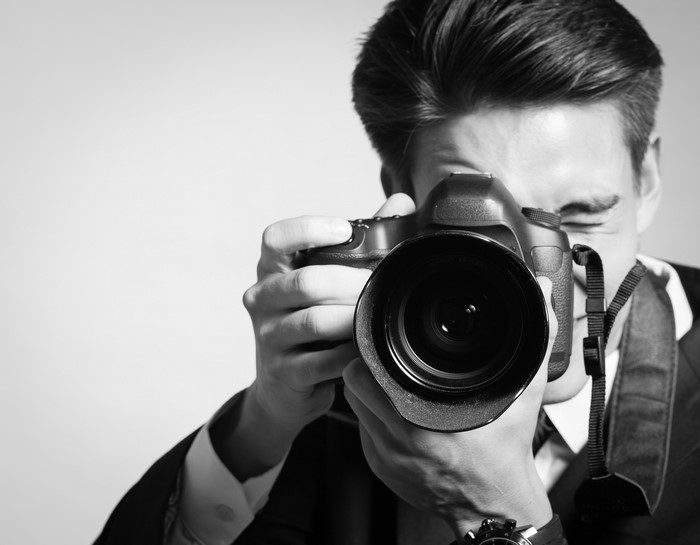 Man in suit taking a photo with a DSLR camera