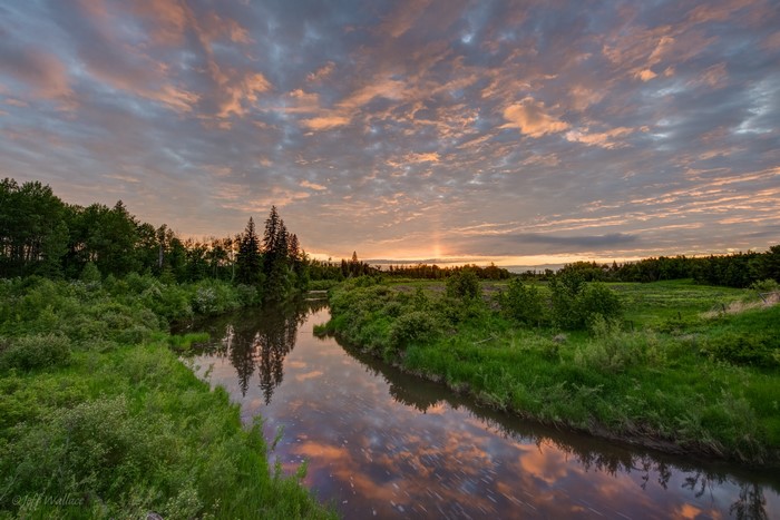 Sunrise over a river with colorful clouds and trees