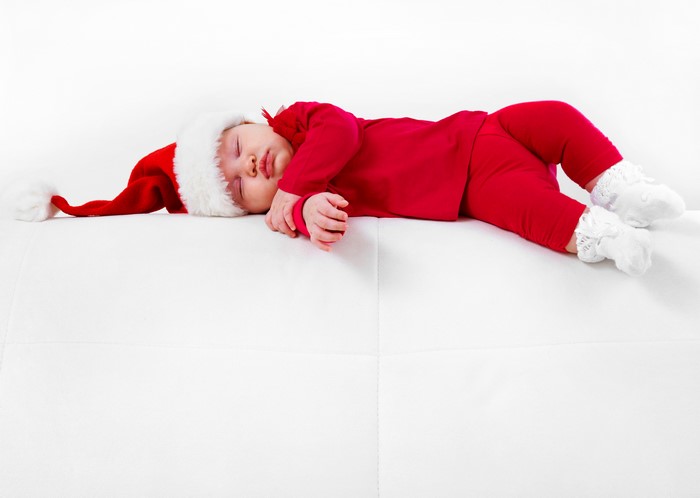 Baby in Santa hat sleeping on white surface