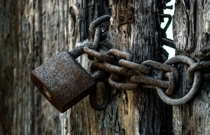 Rusty padlock and chain on weathered wooden door