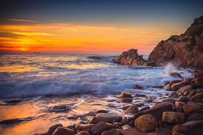 Sunset over rocky coast with waves