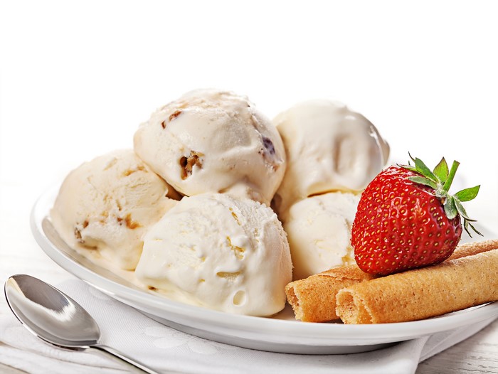 Ice cream with strawberry and wafer rolls on a plate