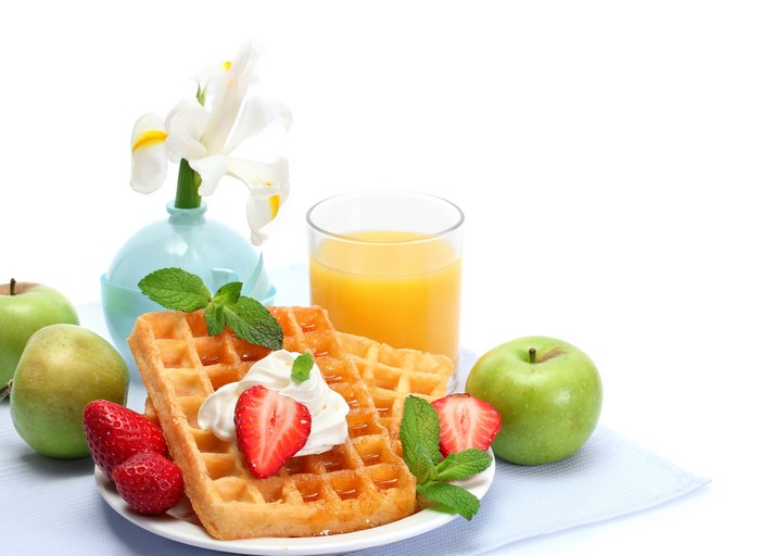 Still-life of waffles, strawberries, apples, juice, and irises