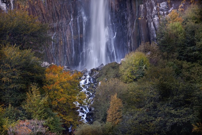 Waterfall cascading down a rocky cliff surrounded by trees