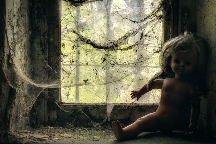 Doll in a spiderweb-covered window