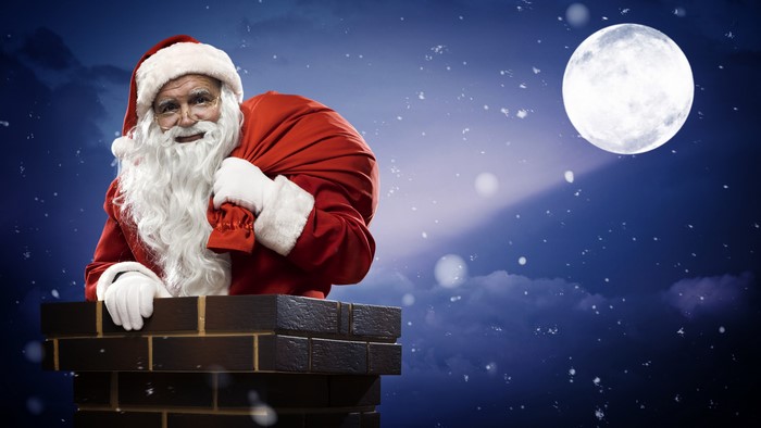 Santa Claus with a sack in a chimney at night