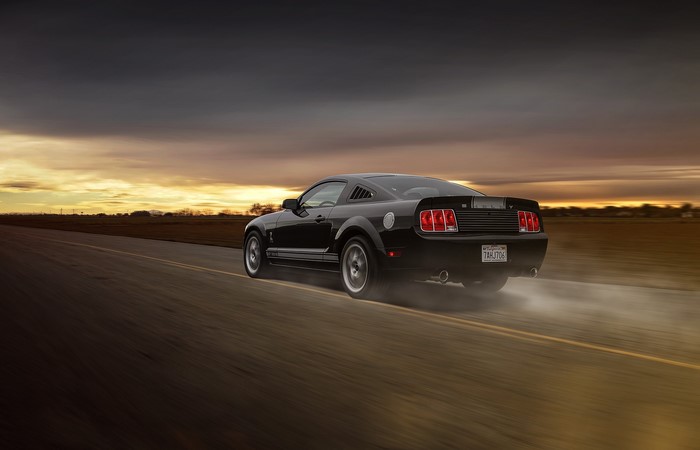 Black Ford Mustang GT 350 driving on a road
