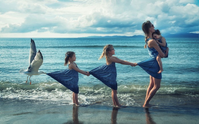 Mother and daughters on the beach with a seagull
