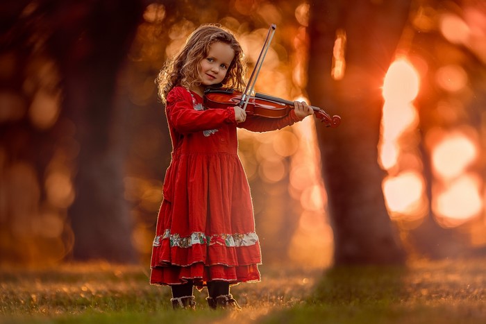 Girl in red dress playing violin outdoors