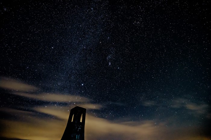 Night sky full of stars over a dark structure