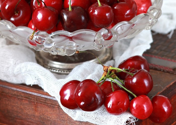 Cherries in a glass bowl on a wooden surface