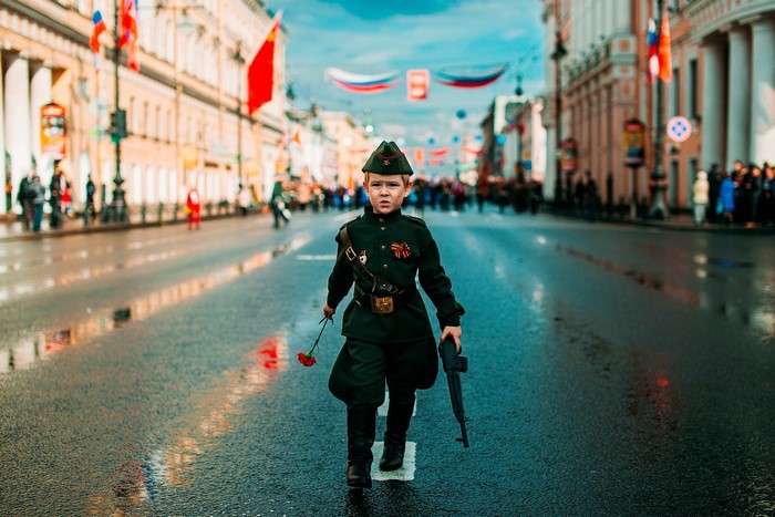 Boy in military uniform holding a flower and toy rifle
