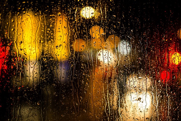 Raindrops on glass with blurred city lights