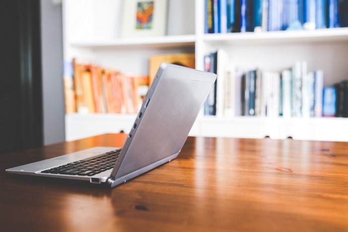 Laptop on a wooden table with bookshelves in the background