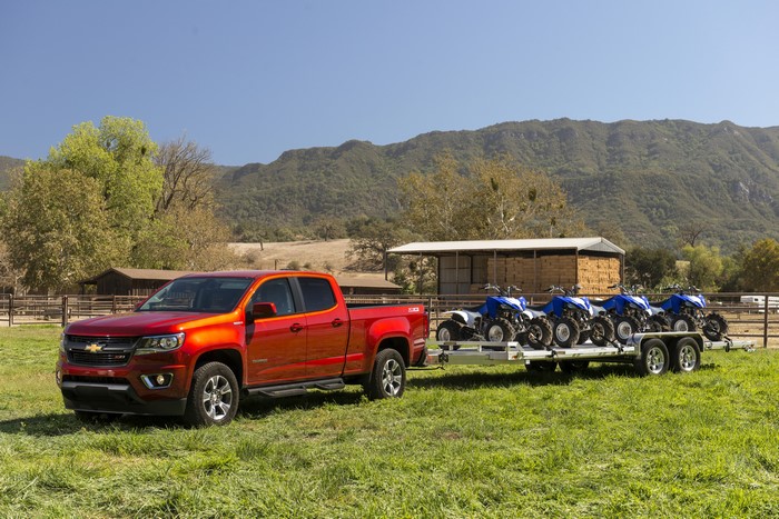 Red Chevrolet Colorado towing ATVs on trailer
