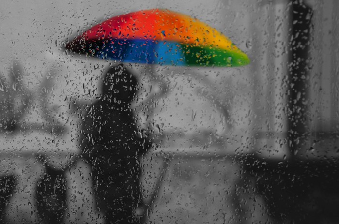 Person with rainbow umbrella in the rain