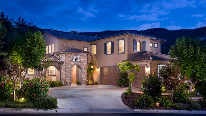 Luxury house with stone accents and manicured landscaping at dusk