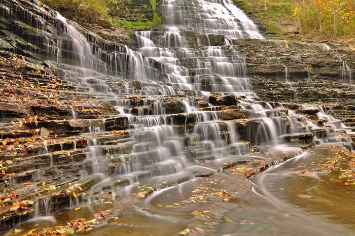 Tiered waterfall in autumn with fallen leaves