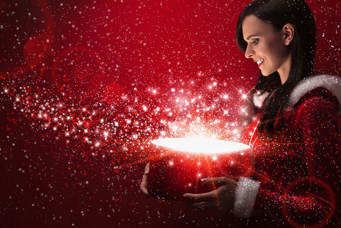 Brunette girl in Santa costume opening a glowing gift box