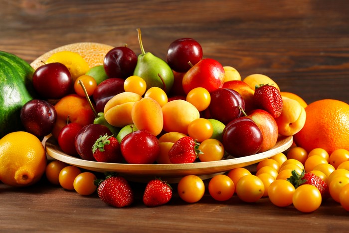Assortment of fresh fruits including strawberries, plums, pears, and oranges