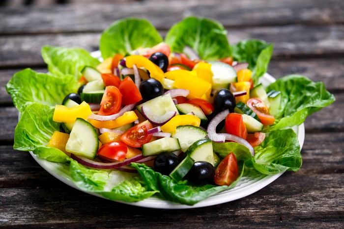 Salad with lettuce, tomatoes, cucumbers, olives, and bell peppers