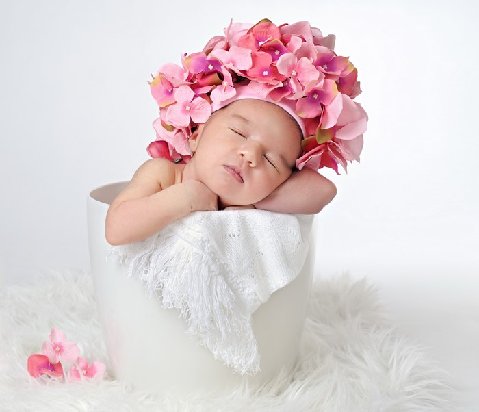 Infant sleeping in a bucket with flowers