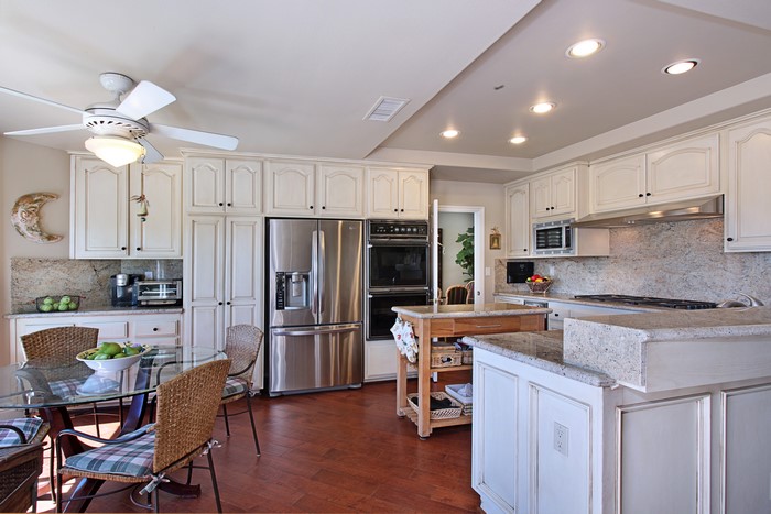 Kitchen with white cabinets, stainless steel appliances, and dining table