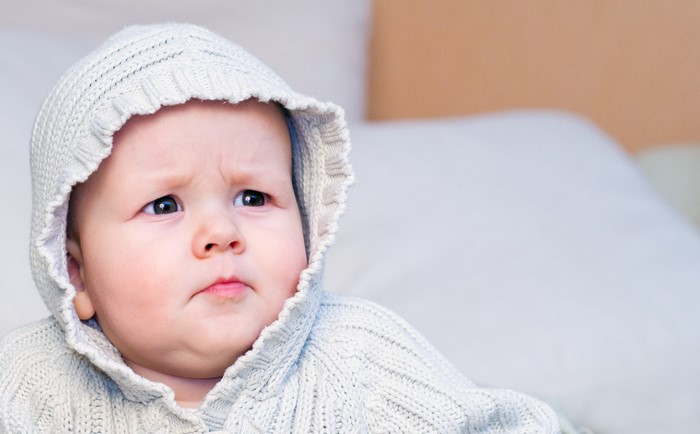 Baby wearing a knitted hood looking to the side