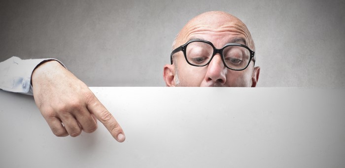 Man wearing glasses pointing at a blank sign