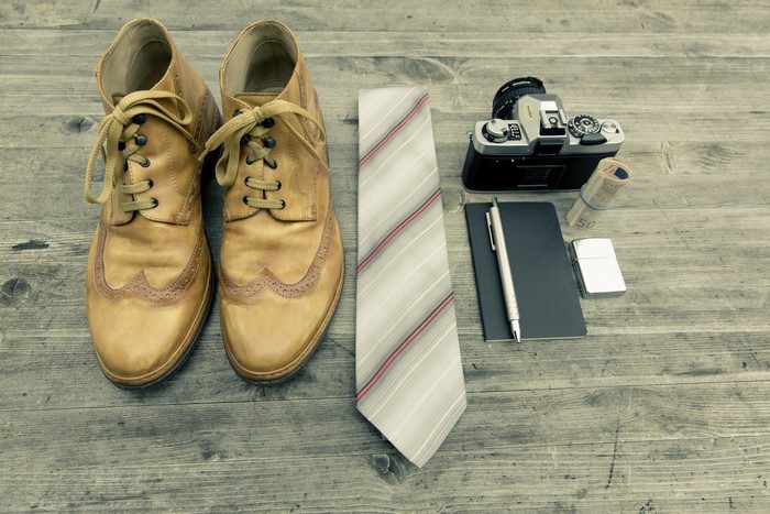 Boots, Necktie, Camera, and Money on Wooden Surface
