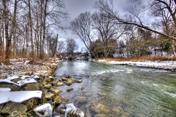 Winter river with snow-covered rocks and trees