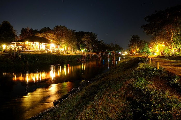 Night scene of a river with a restaurant and bridge in Pai, Thailand