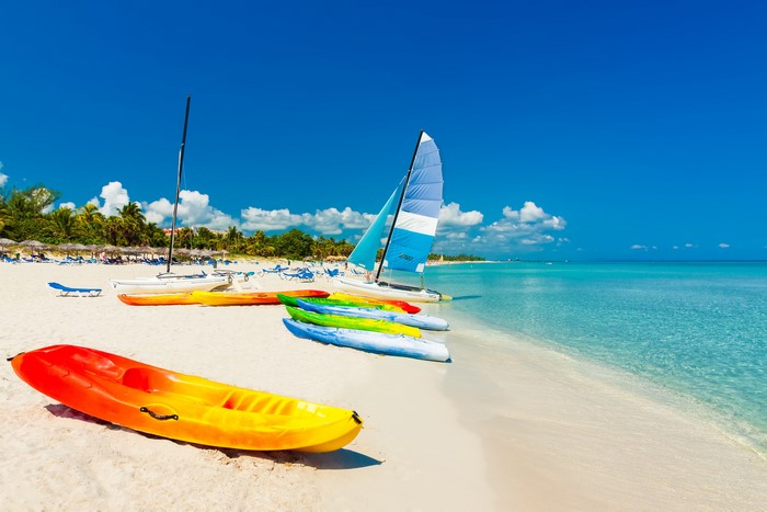 Kayaks and sailboats on a tropical beach