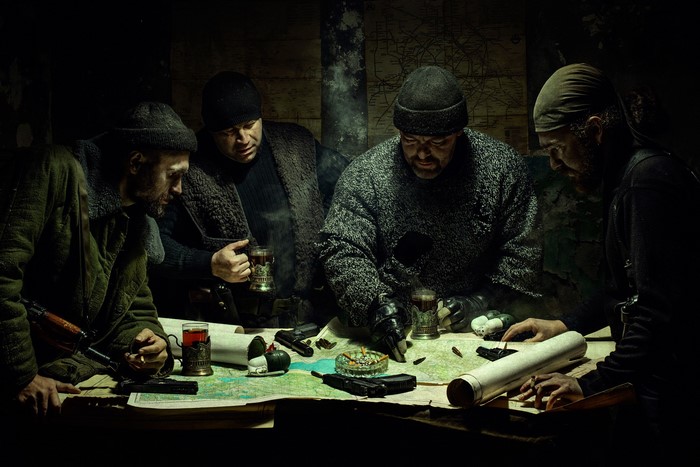 Men gathered around a table with maps and weapons