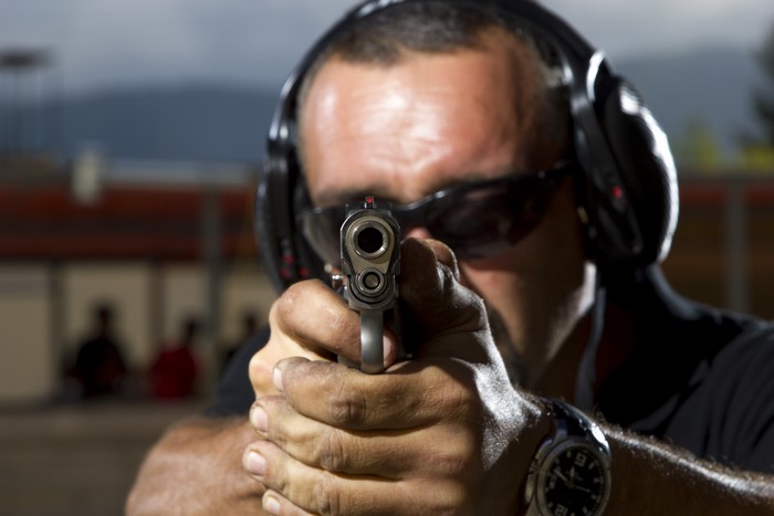 Man aiming a pistol with hearing protection