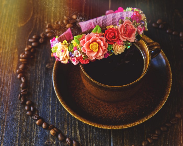 Coffee cup with floral headband and coffee beans