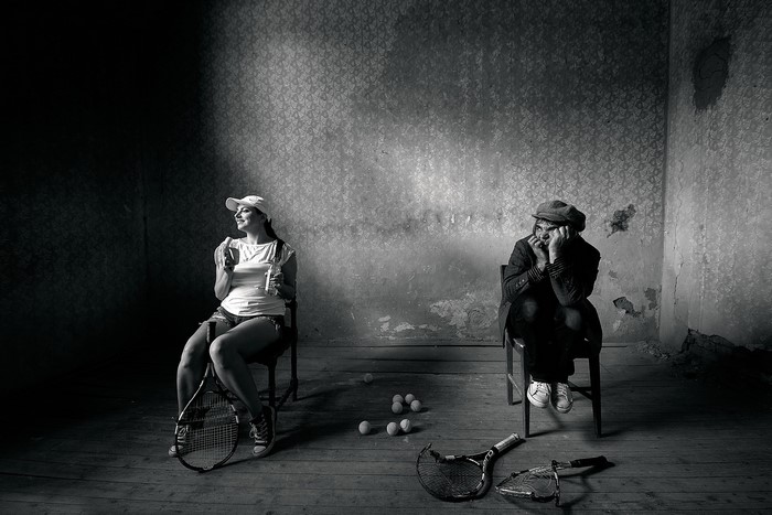 Man and woman with tennis rackets in a room