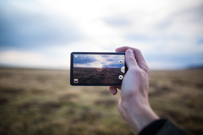 Hand holding Samsung Galaxy smartphone taking picture of landscape