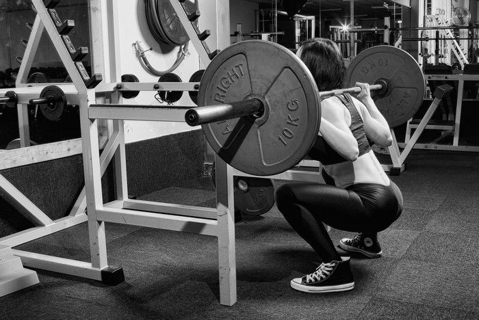 Woman performing barbell squats in a gym