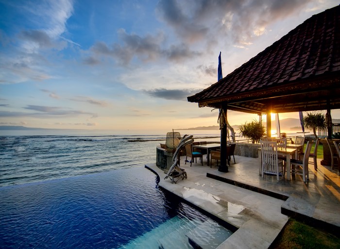 Infinity pool and gazebo by the sea at sunset